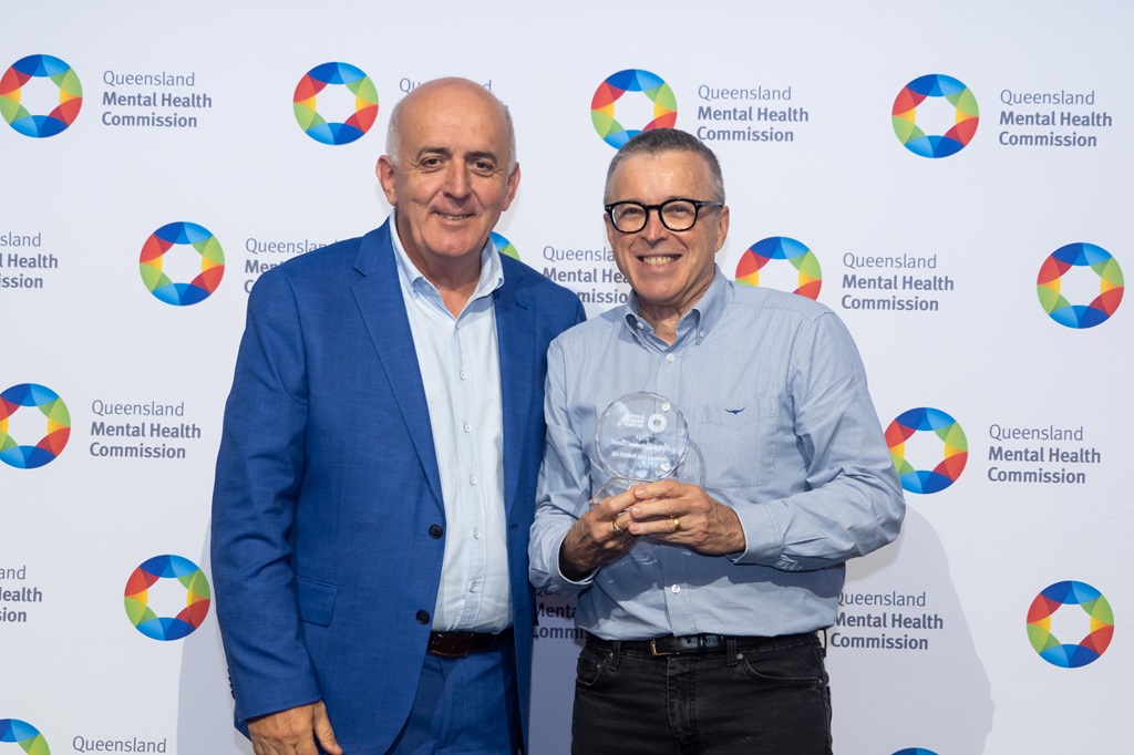 Professor John McGrath standing with Commissioner Ivan Frkovic receiving the award