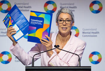 Image of Michelle Sanders at Leading Reform Summit holding the Commission's Lived-Living Experience Commitment document